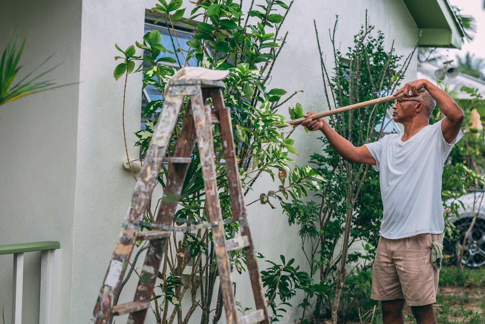 Pintor en una escalera pintando el exterior de una casa
