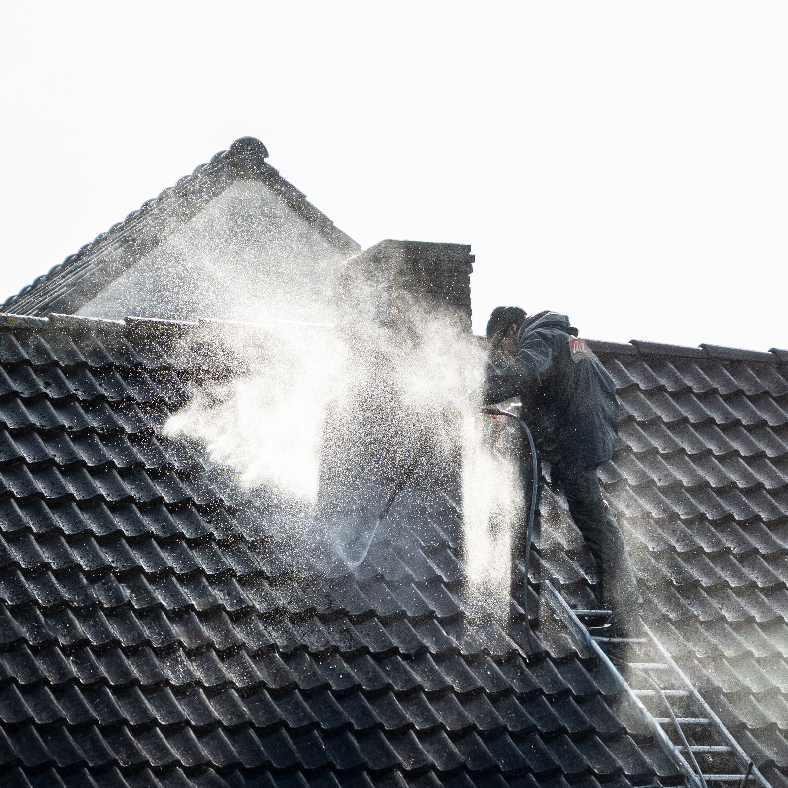Trabajador haciendo soft wash a un techo de teja de barril